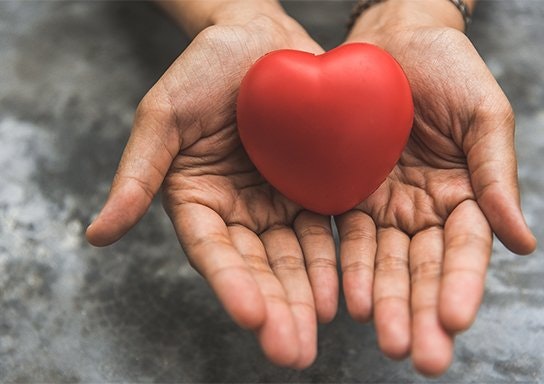 Hands holding a red heart.