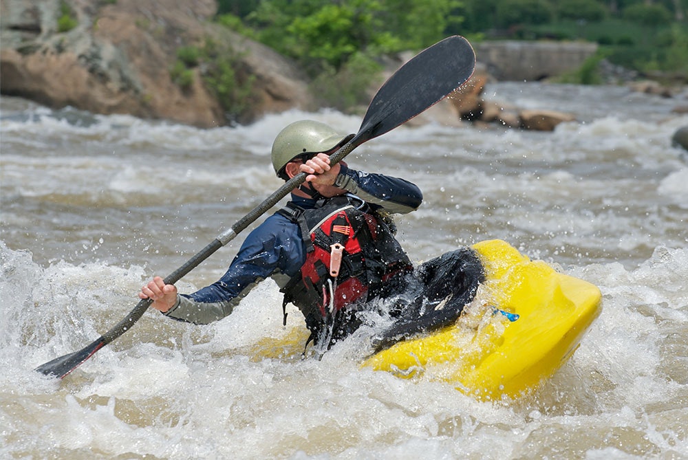 A kayaker navigating rough river waters.