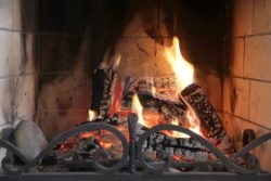 A cozy fireplace with burning logs and flames inside a brick hearth.