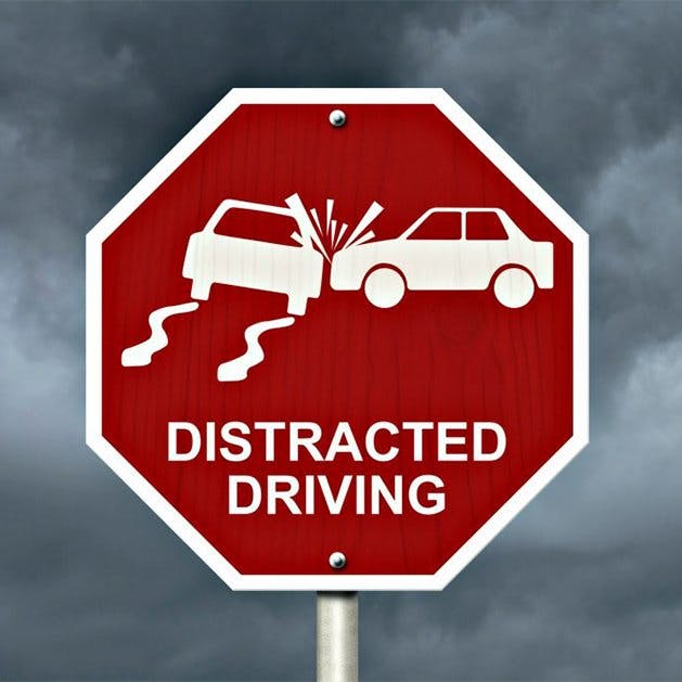 A red traffic sign warning against distracted driving with car collision graphic.