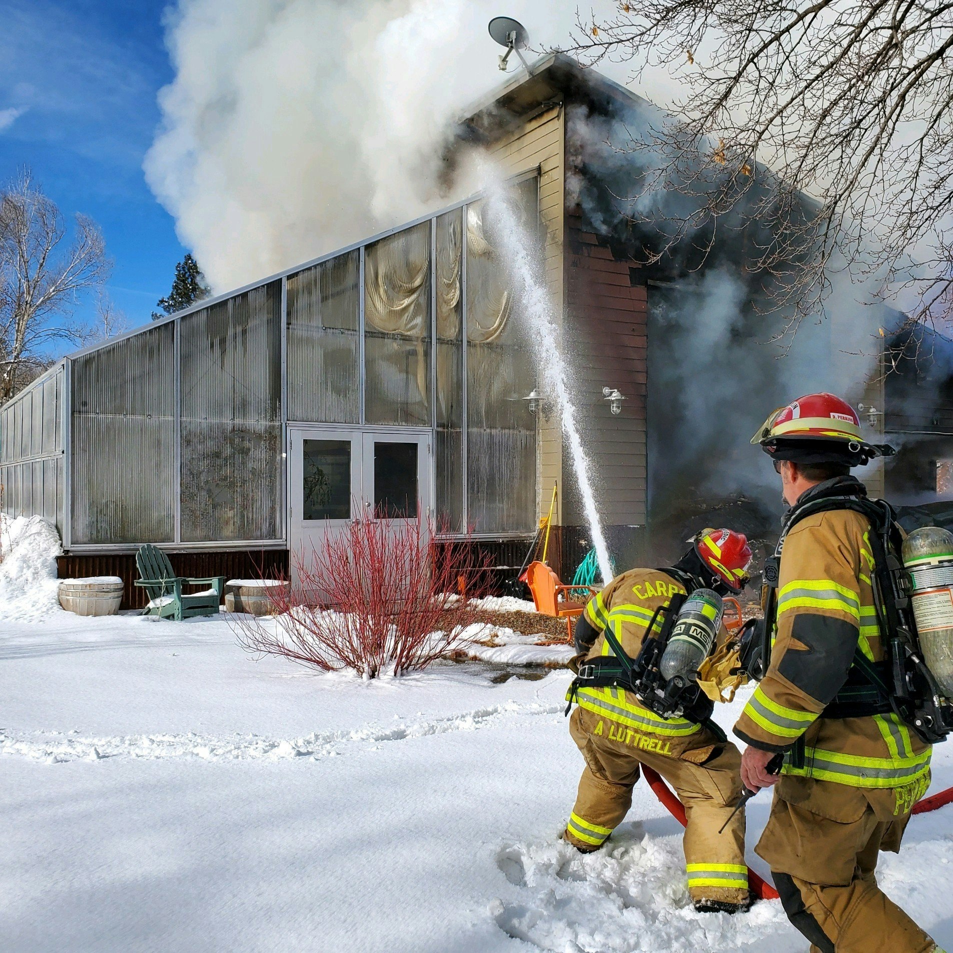 Firefighters extinguishing a house fire in snowy surroundings.