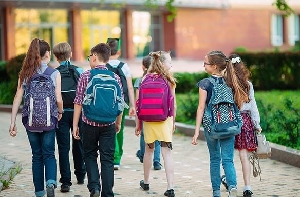 Group of kids with backpacks walking outside.