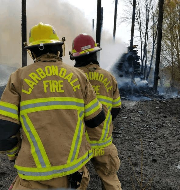 Two firefighters facing a smoke-filled scene with "CARBONDALE FIRE" on their jackets.