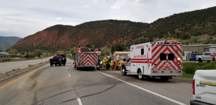 A traffic accident with emergency responders and vehicles on a road, with hills in the background.