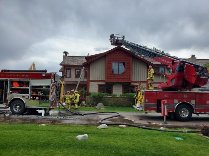 Firefighters using a ladder truck near a house, possibly responding to an emergency.