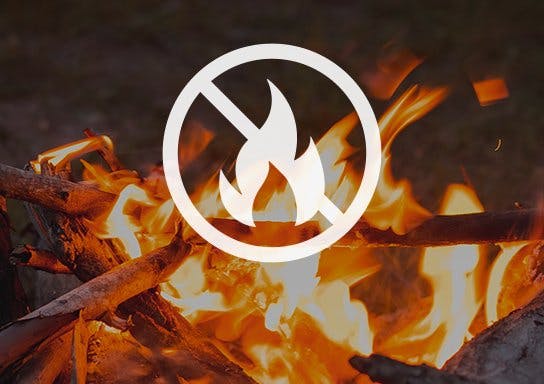 A campfire with a "no fire" symbol superimposed, indicating a fire ban or no burning allowed.