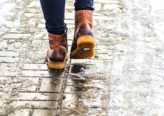 Someone walking on a wet cobblestone pavement wearing boots.