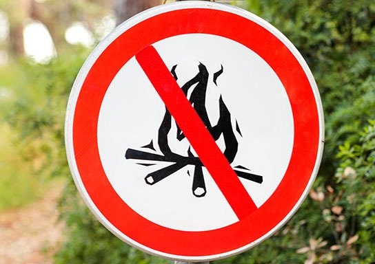 A no campfires sign with a red circle and slash over a pictogram of a fire and sticks.