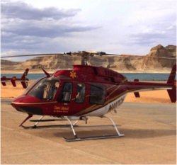 A red helicopter on the ground with scenic rocky background.