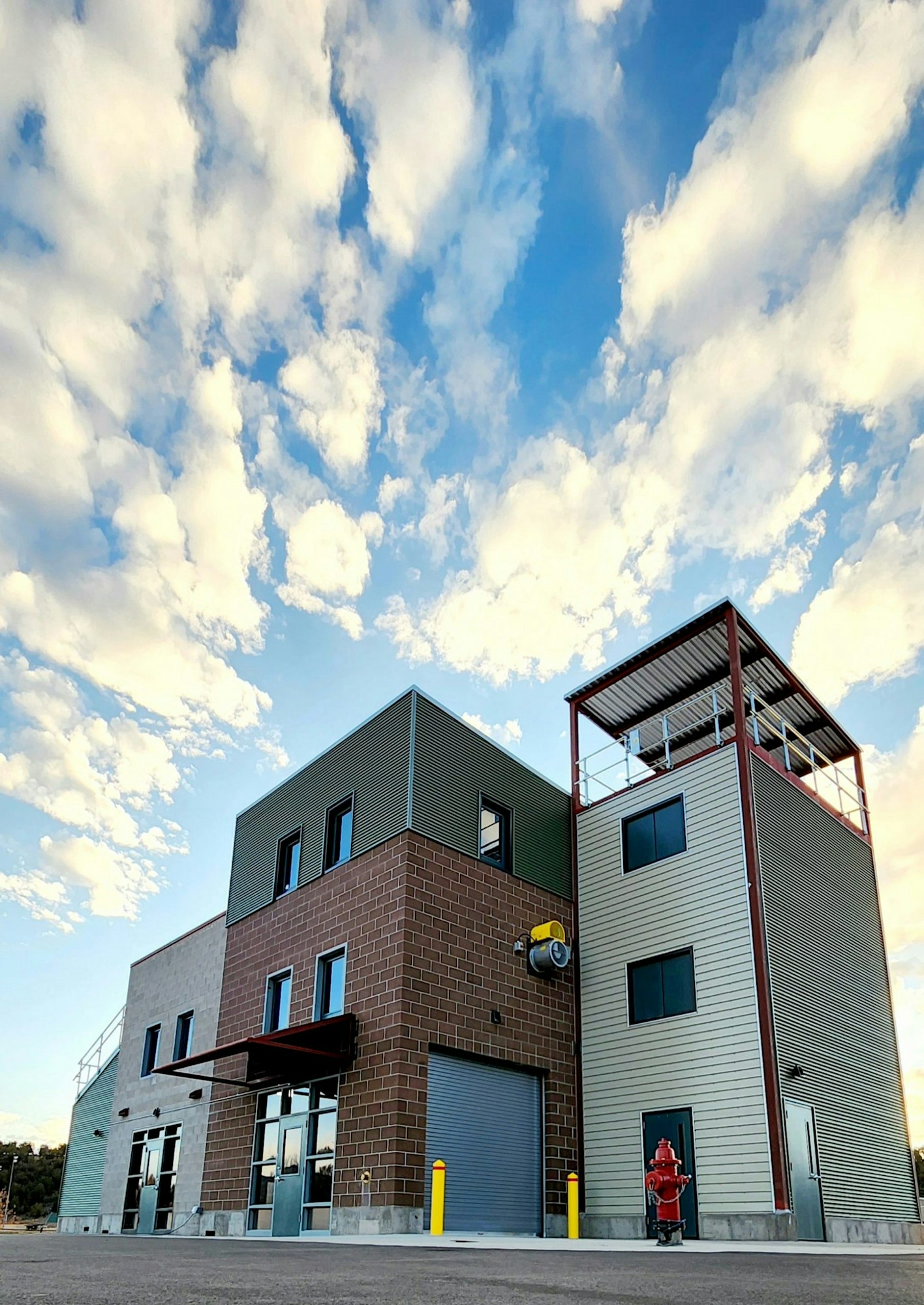 Modern industrial building under a vibrant sky with fluffy clouds.