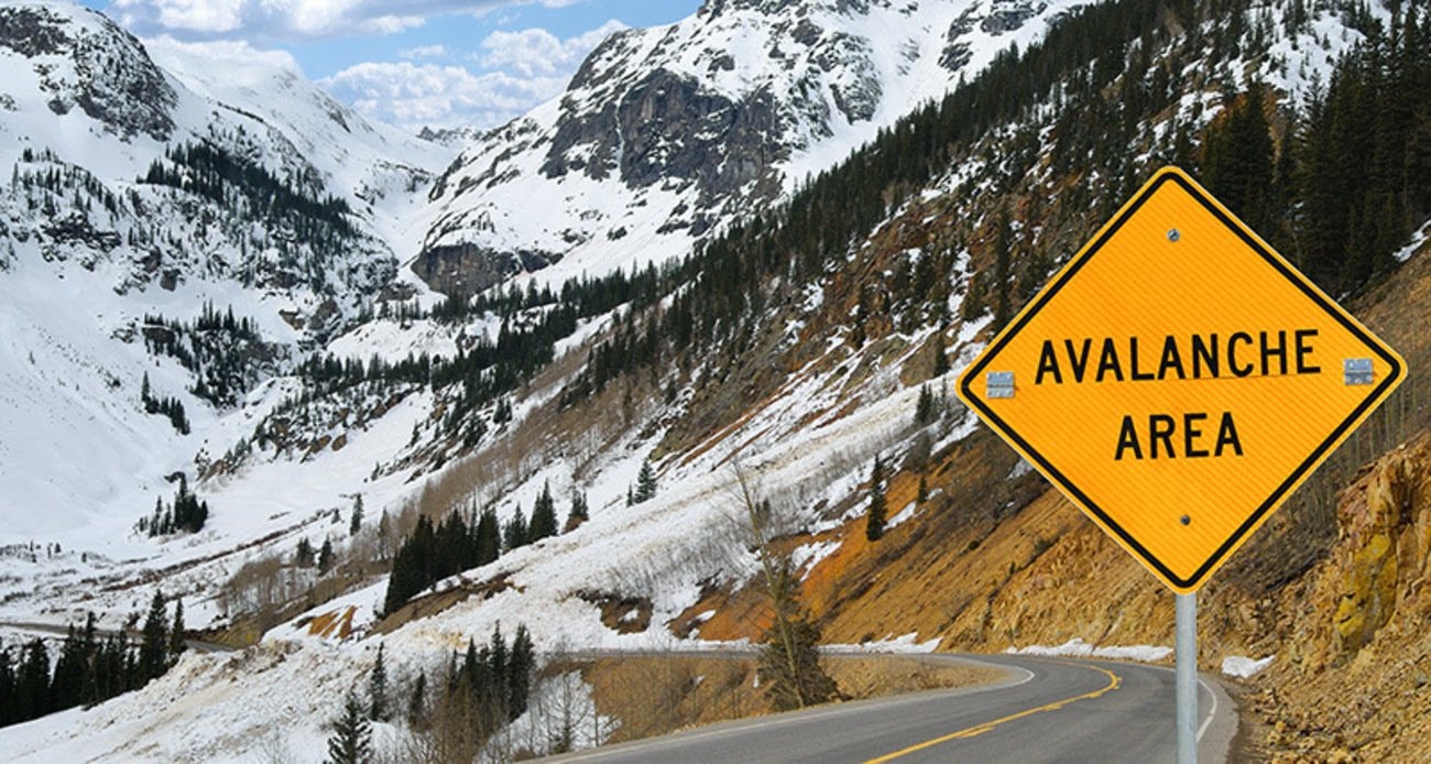 Mountain road with an "Avalanche Area" warning sign. Snowy landscape.