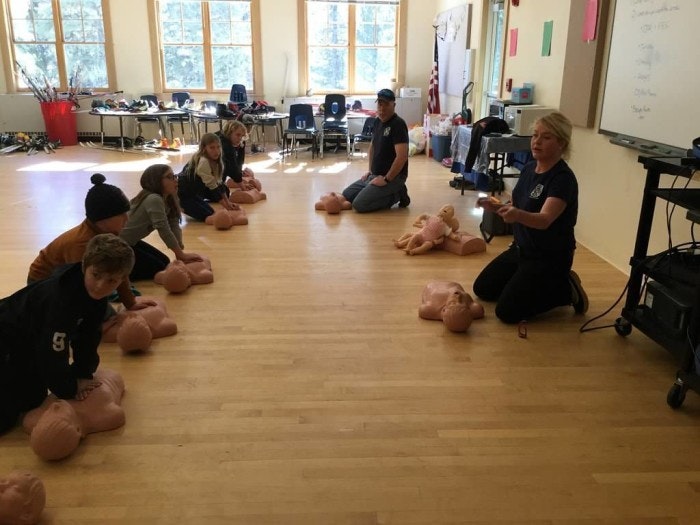 A CPR class with instructors and students practicing on mannequins.