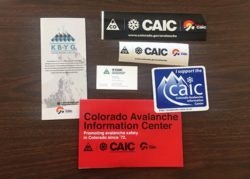 Various items including a pamphlet, stickers, and a business card, probably related to the Colorado Avalanche Information Center.