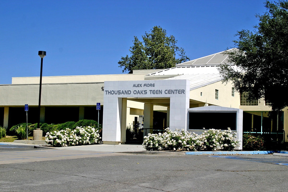 Entrance of the Alex Fiore Thousand Oaks Teen Center, surrounded by white flowers and a clear blue sky.