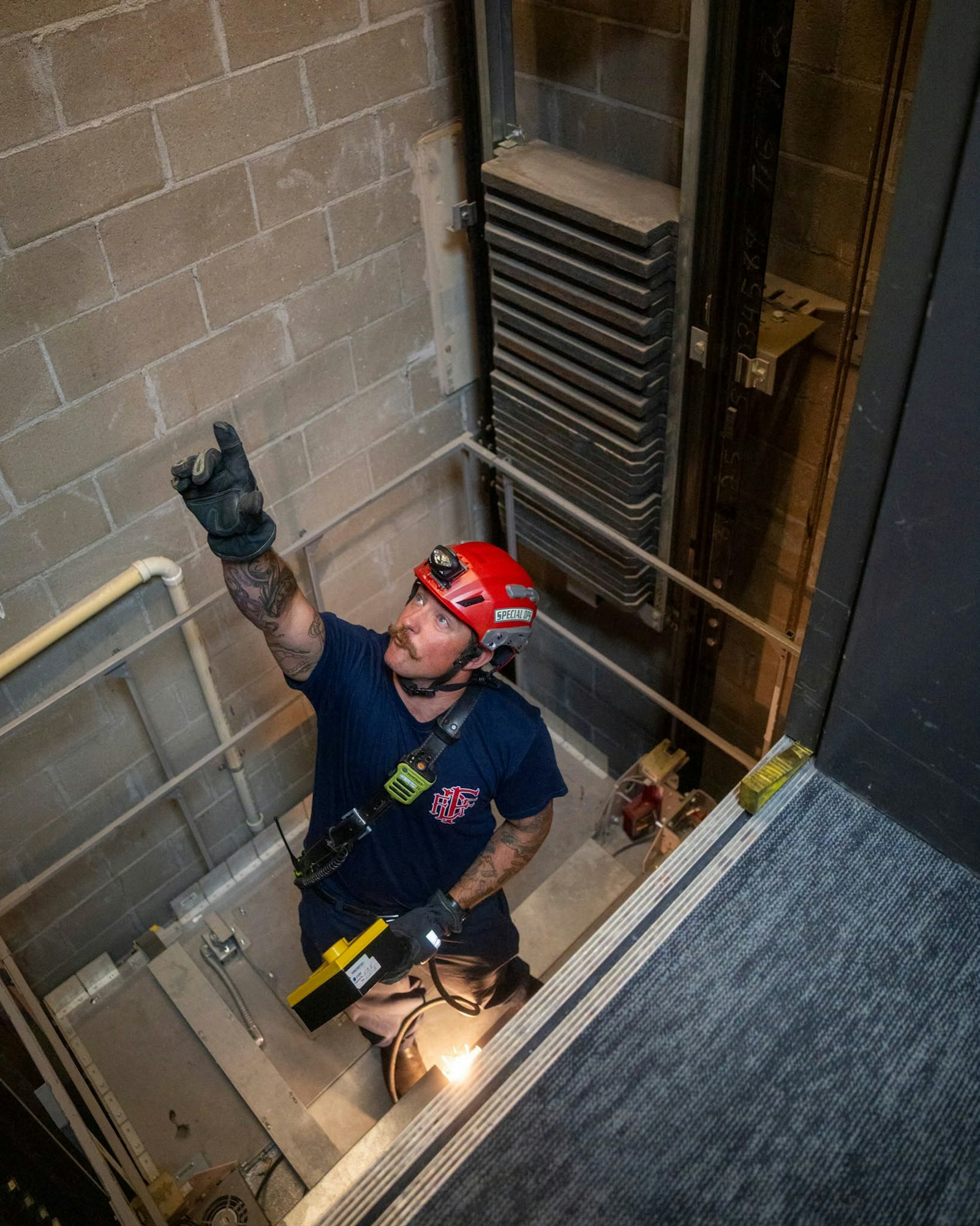 May contain: clothing, hardhat, helmet, person, worker, glove, face, head, photography, portrait, door, floor, architecture, building, house, housing, and staircase