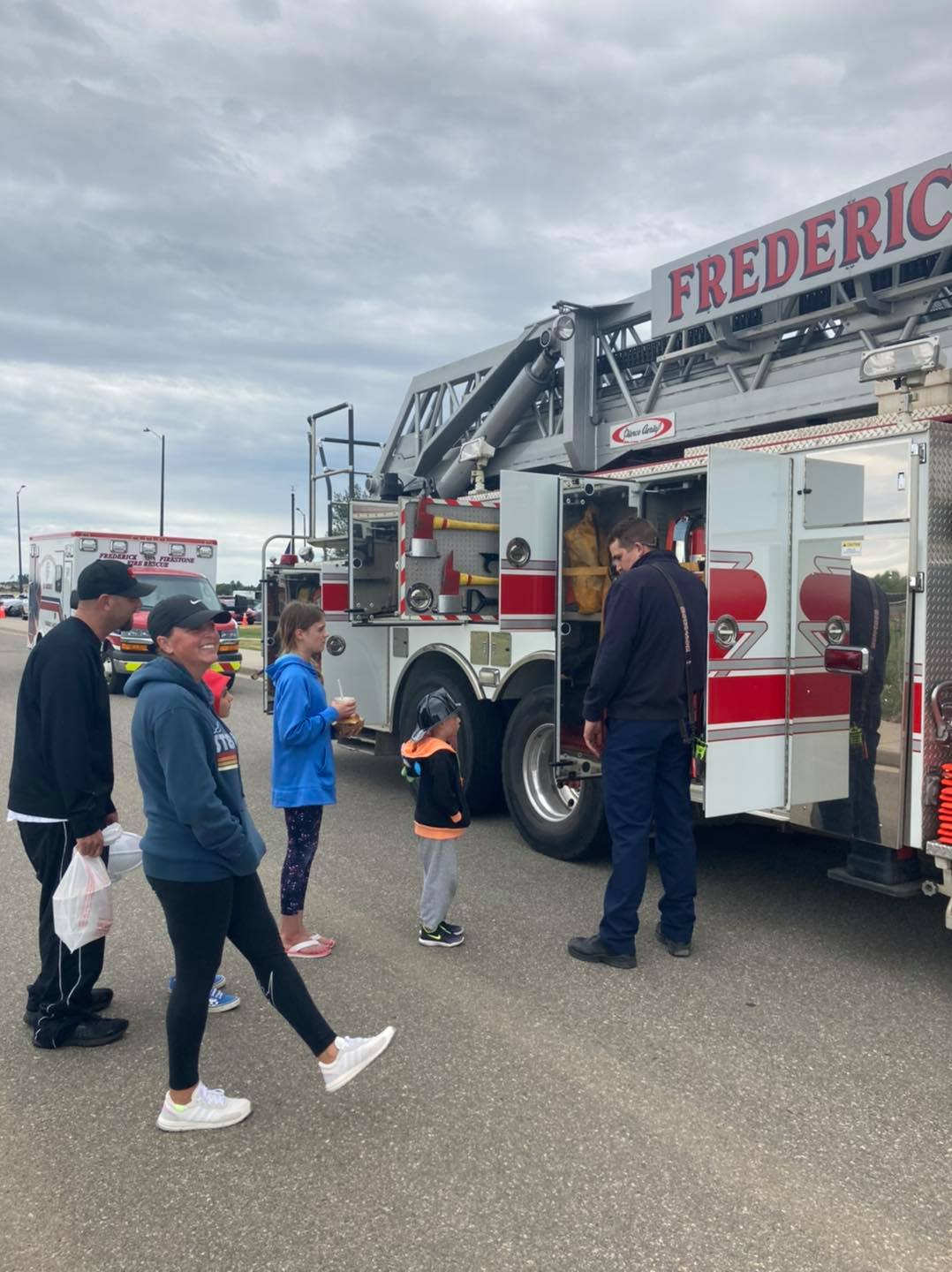 A group of people and a firefighter near a fire truck labeled "FREDERICK."