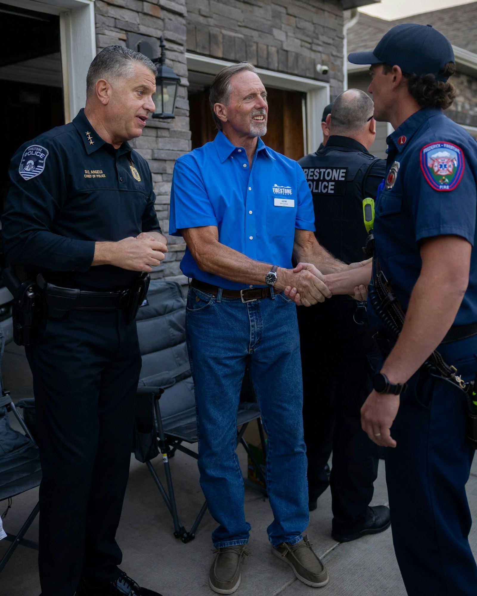 A meeting with police officers and a community member, featuring handshakes and friendly interactions outside a building.