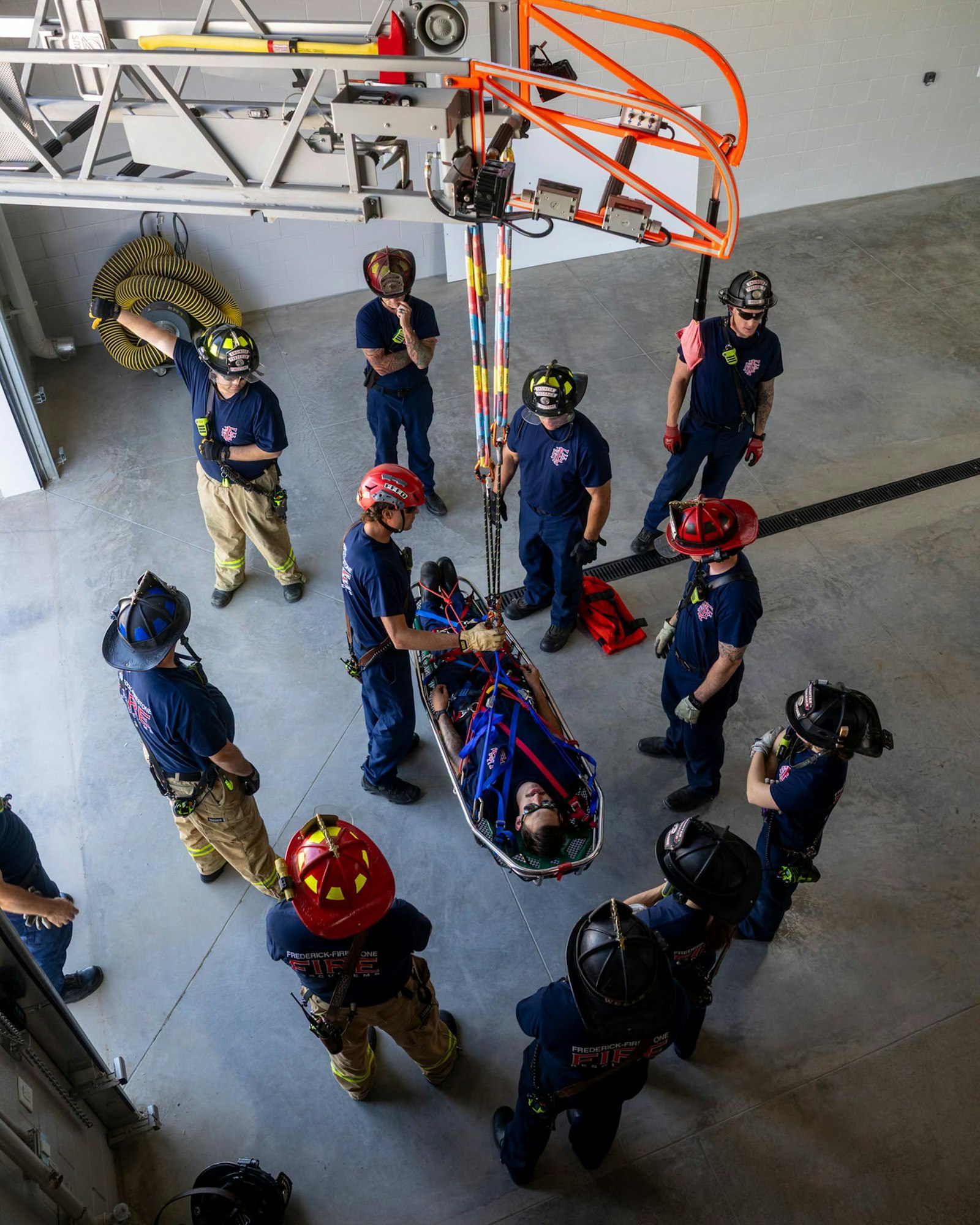 Firefighters conduct a training exercise involving rescue techniques with a simulated patient in a harness.