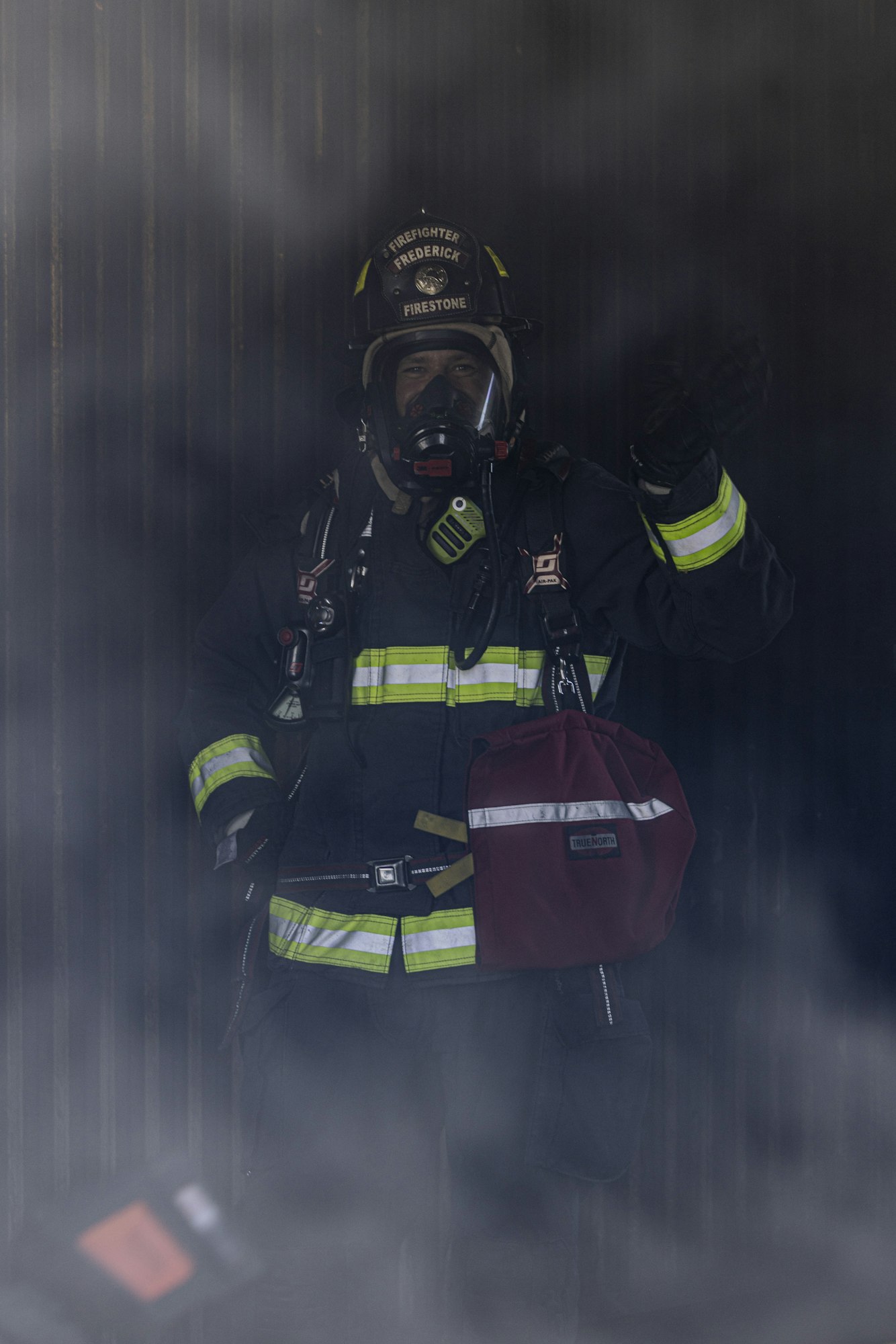 A firefighter in protective gear stands in a smoky environment, ready for action.