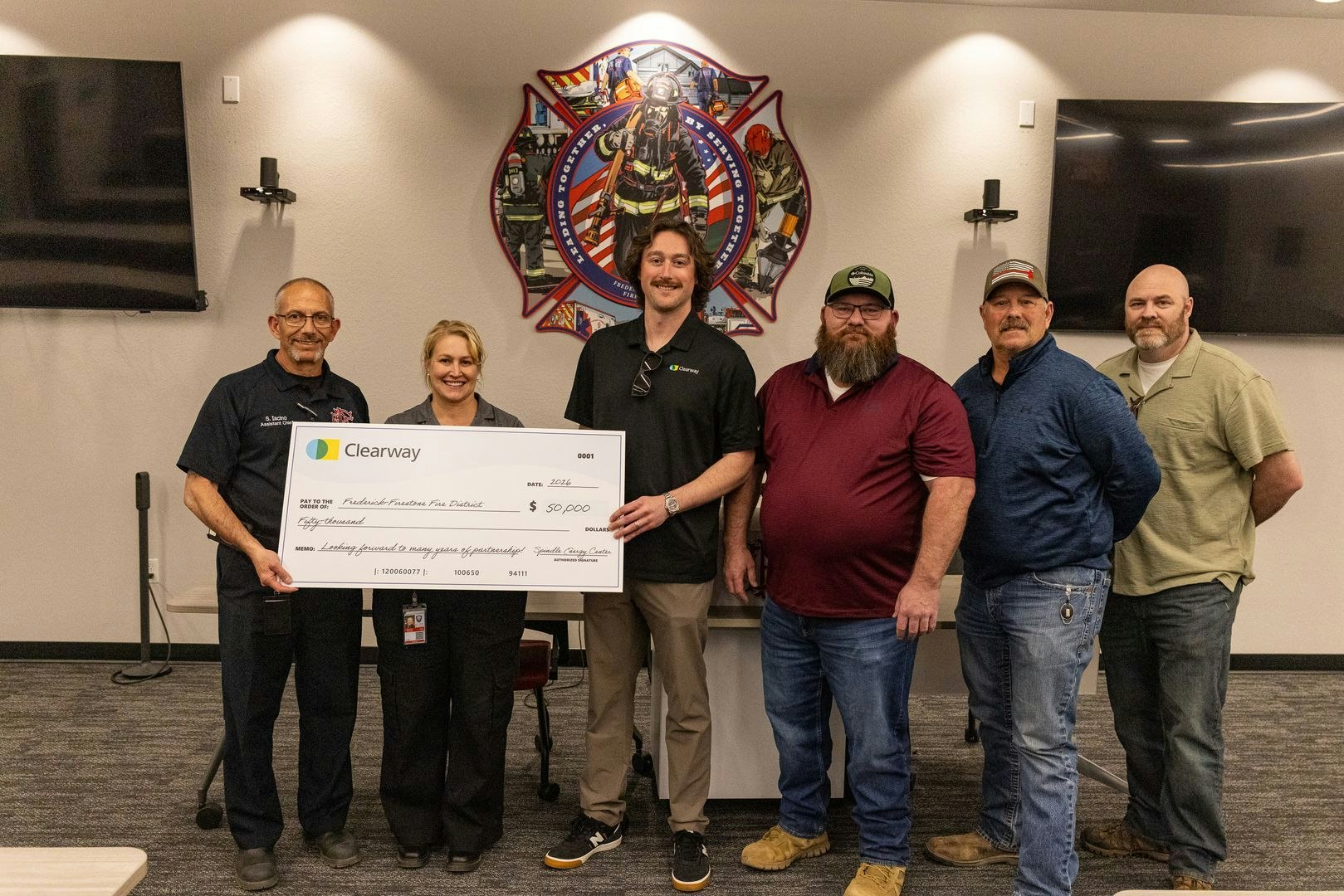 A group poses with a large check for $50,000 for the Frederick-Firestone Fire District, sponsored by Clearway.