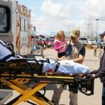 Medical personnel with a stretcher outdoors near an ambulance.
