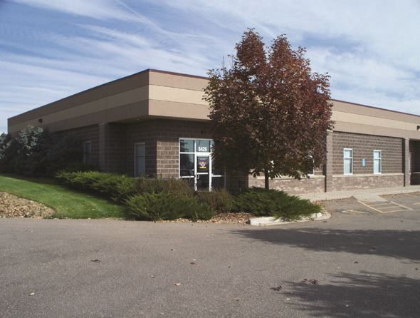Commercial building with a "For Lease" sign, parking lot, and a tree in front.
