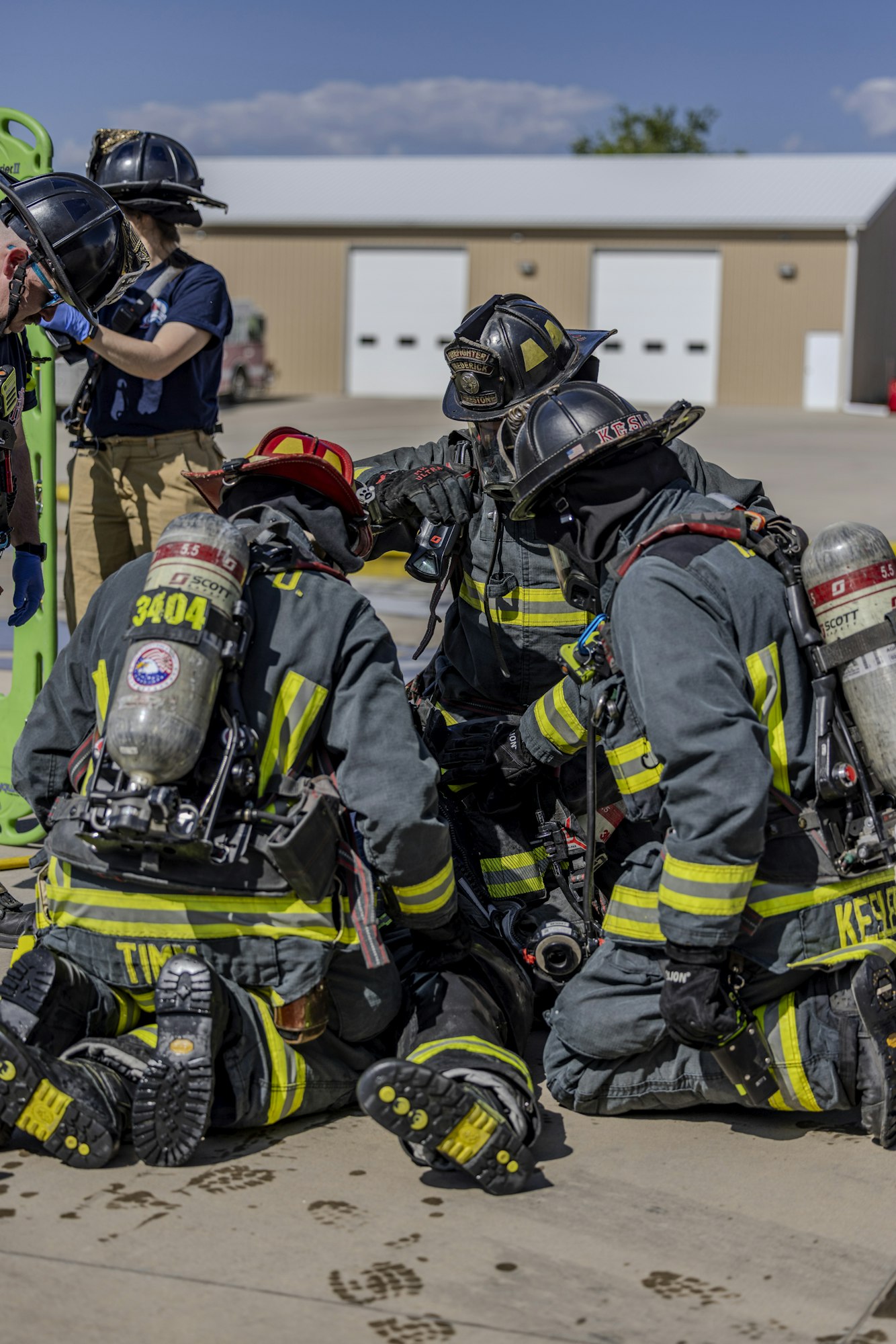 Firefighters in gear are collaborating on a task outdoors, demonstrating teamwork and safety protocols in training or emergency response.