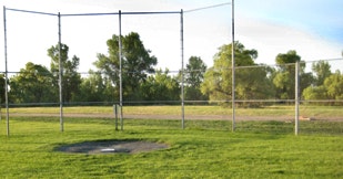A baseball mound and backstop on a sunny day.