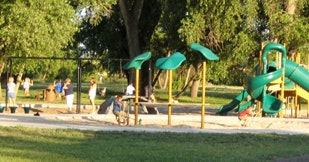A playground with slides and people enjoying a sunny day.