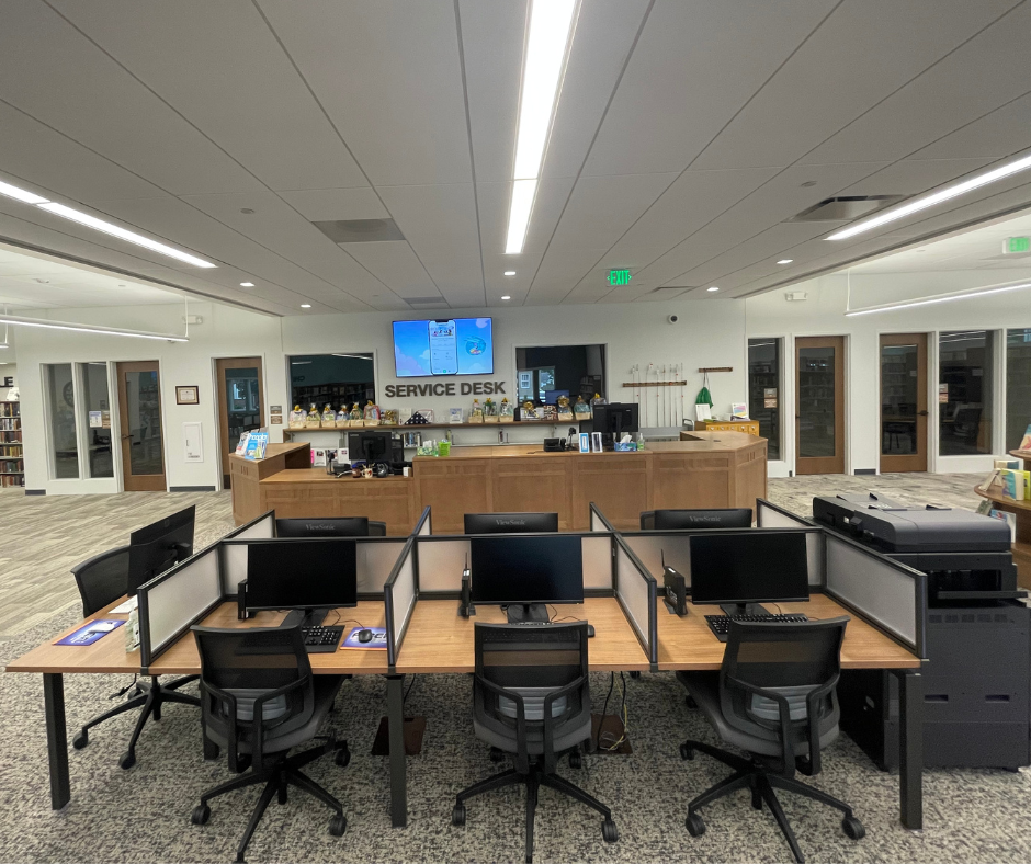 Library service desk area with computers, chairs, a printer, and a large "SERVICE DESK" sign.