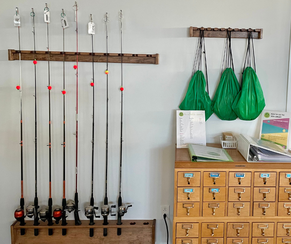 Fishing rods, green bags on hooks, and a wooden cabinet with small drawers and informational signs.