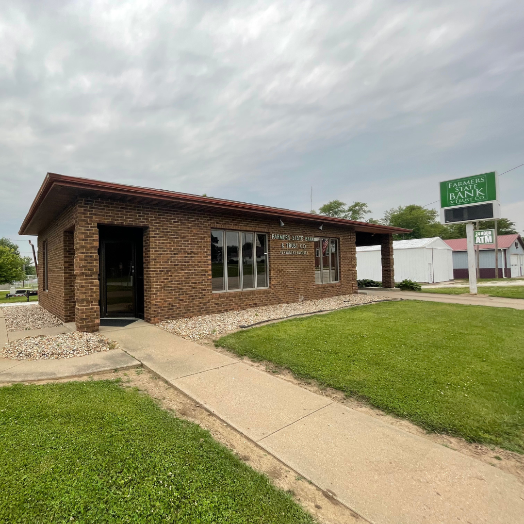 Brick building labeled "Farmers State Bank & Trust Co." with a sign and grassy area.