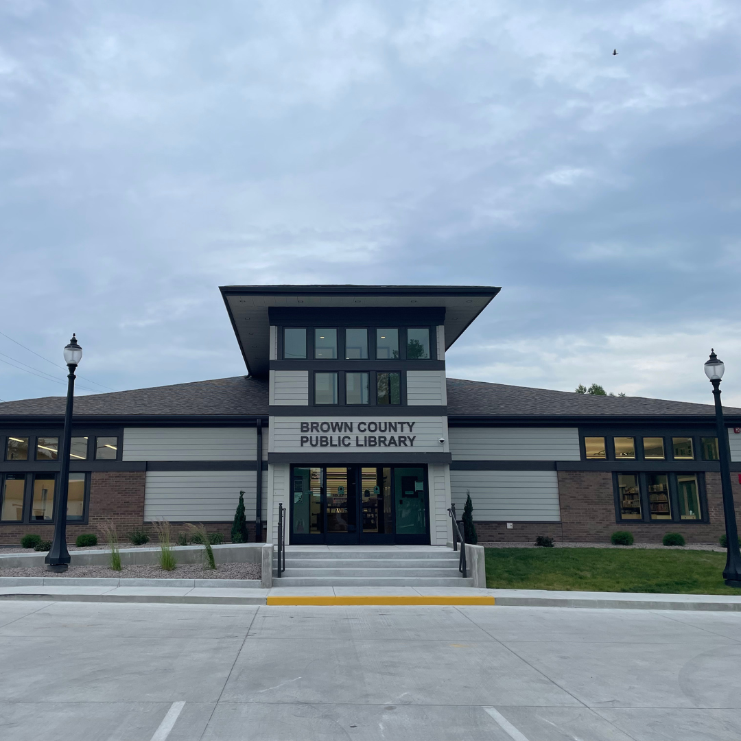 Brown County Public Library building with two lampposts and a cloudy sky.