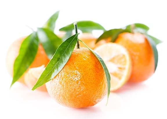 Fresh oranges with green leaves, one cut in half, on a white background.