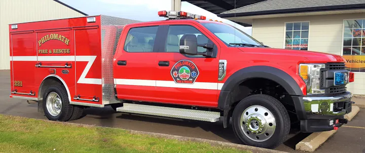 A red fire and rescue truck marked "Philomath Fire & Rescue" with emergency lights and equipment for firefighting.