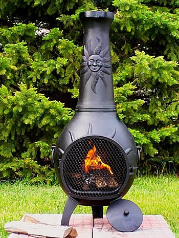 Black chimnea with fire burning, placed on cement pavers