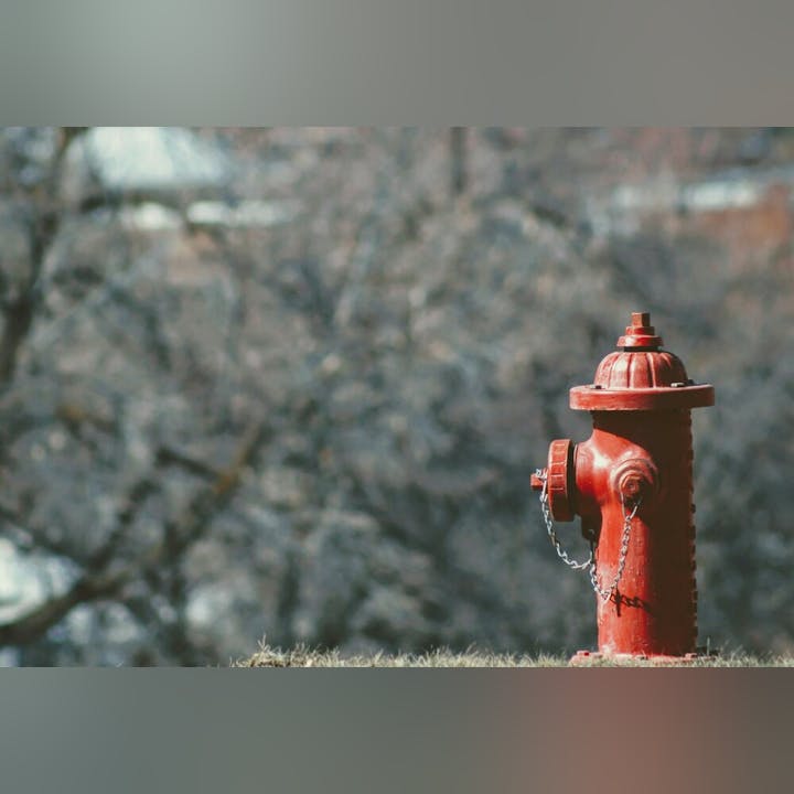 A red fire hydrant with a chain, against a blurred background.