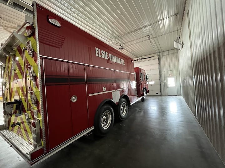 Red firetruck parked inside a station bay with "ELSIE-UNADILLA" text on the side.