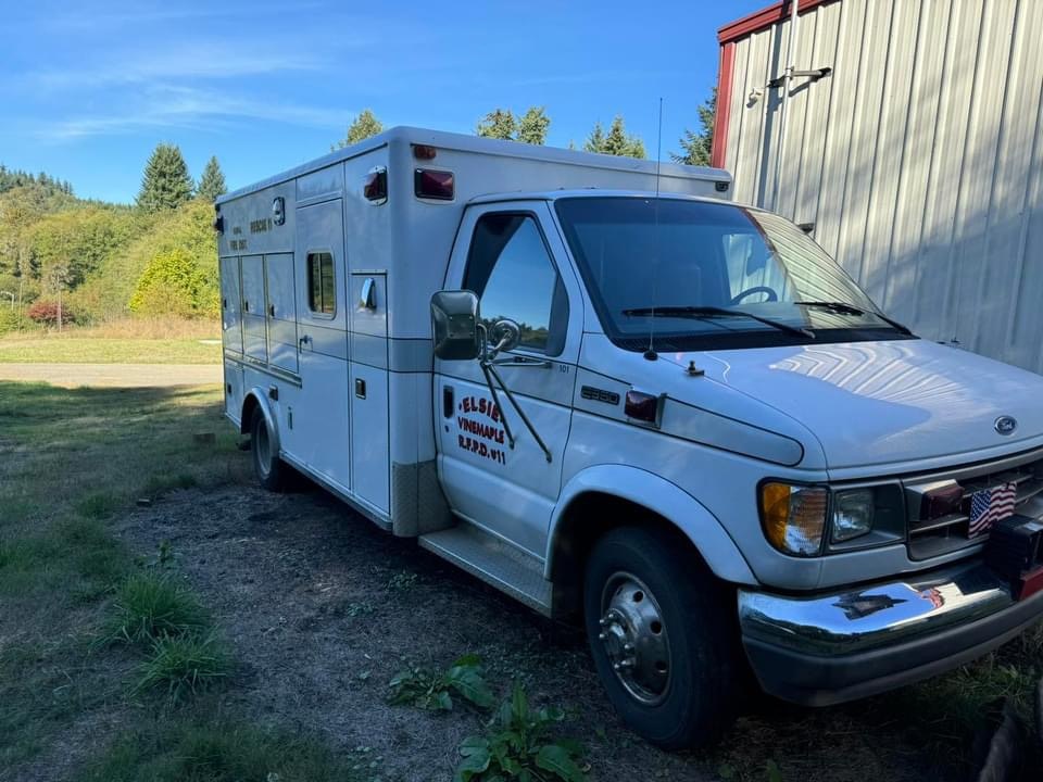 An ambulance parked outdoors near a building with clear skies in the background.