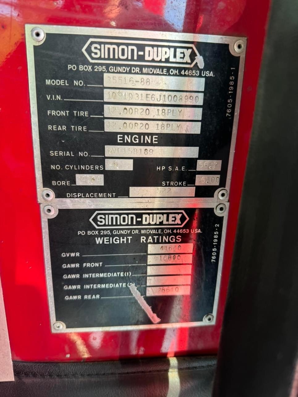 A vehicle specification plate for Simon-Duplex with model number, V.I.N., tire size, engine details, and weight ratings.