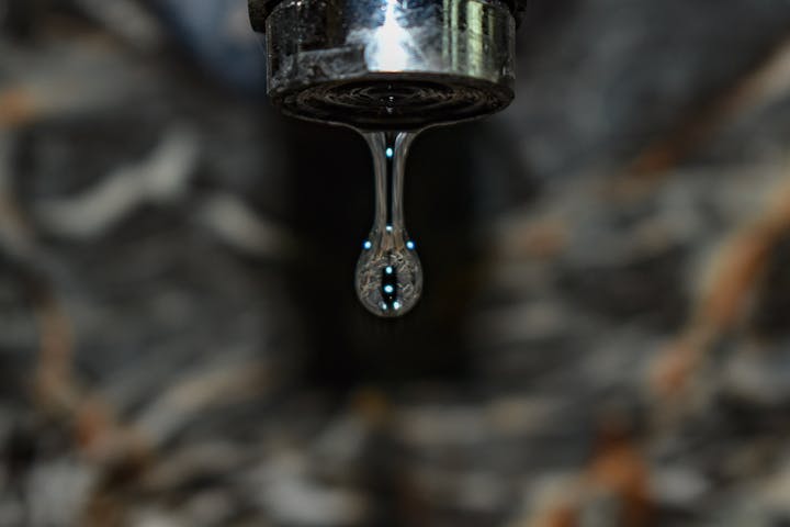 A close-up of a water droplet falling from a faucet.