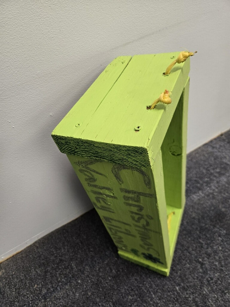 A green wooden box with a somewhat rough finish, possibly for decoration, with small protrusions on one side.