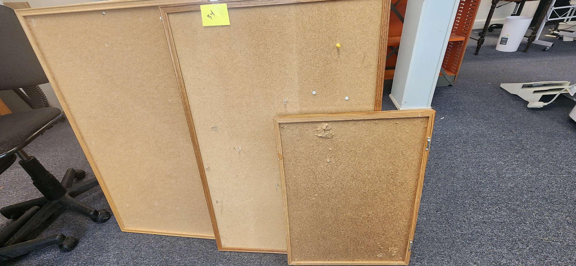 The image shows three cork boards with wooden frames leaning against each other on a carpeted floor.