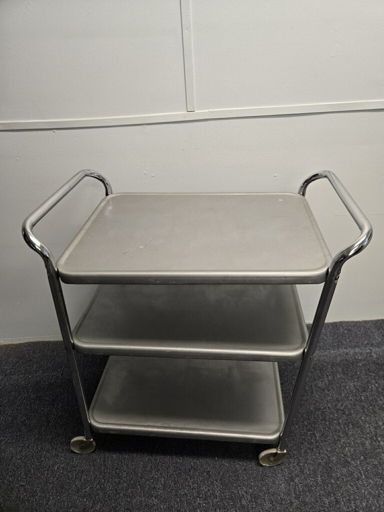 A three-tier metal cart with a sleek design, featuring wheels for mobility, ideal for storage or serving items.
