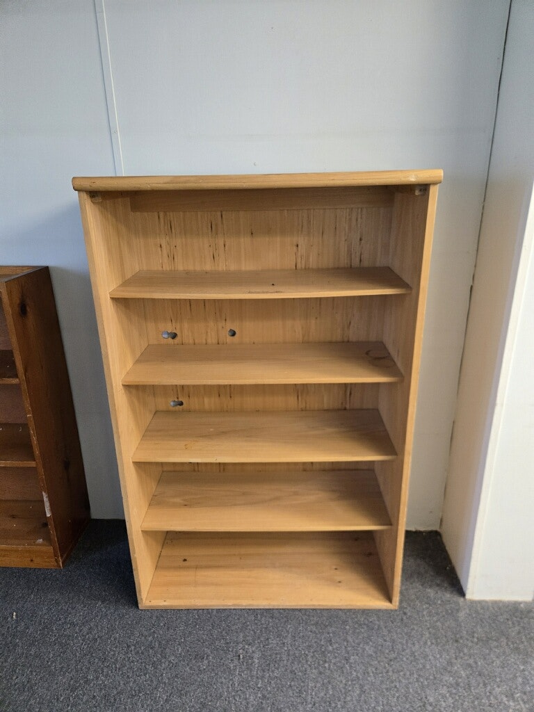 A wooden bookshelf with five shelves, currently empty and situated on a carpeted floor.
