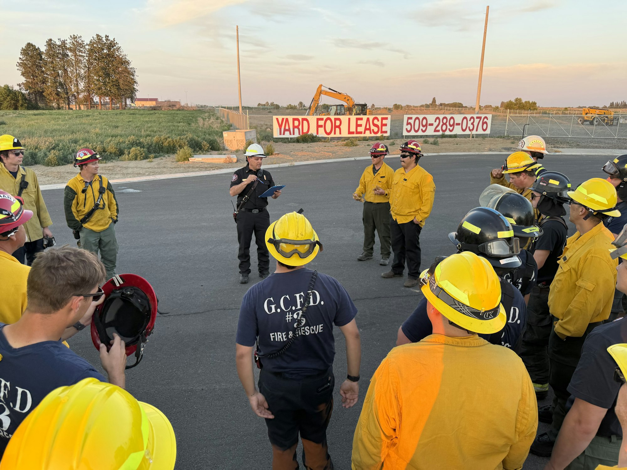 Group of firefighters in yellow wildland gear having a drill outdoors.