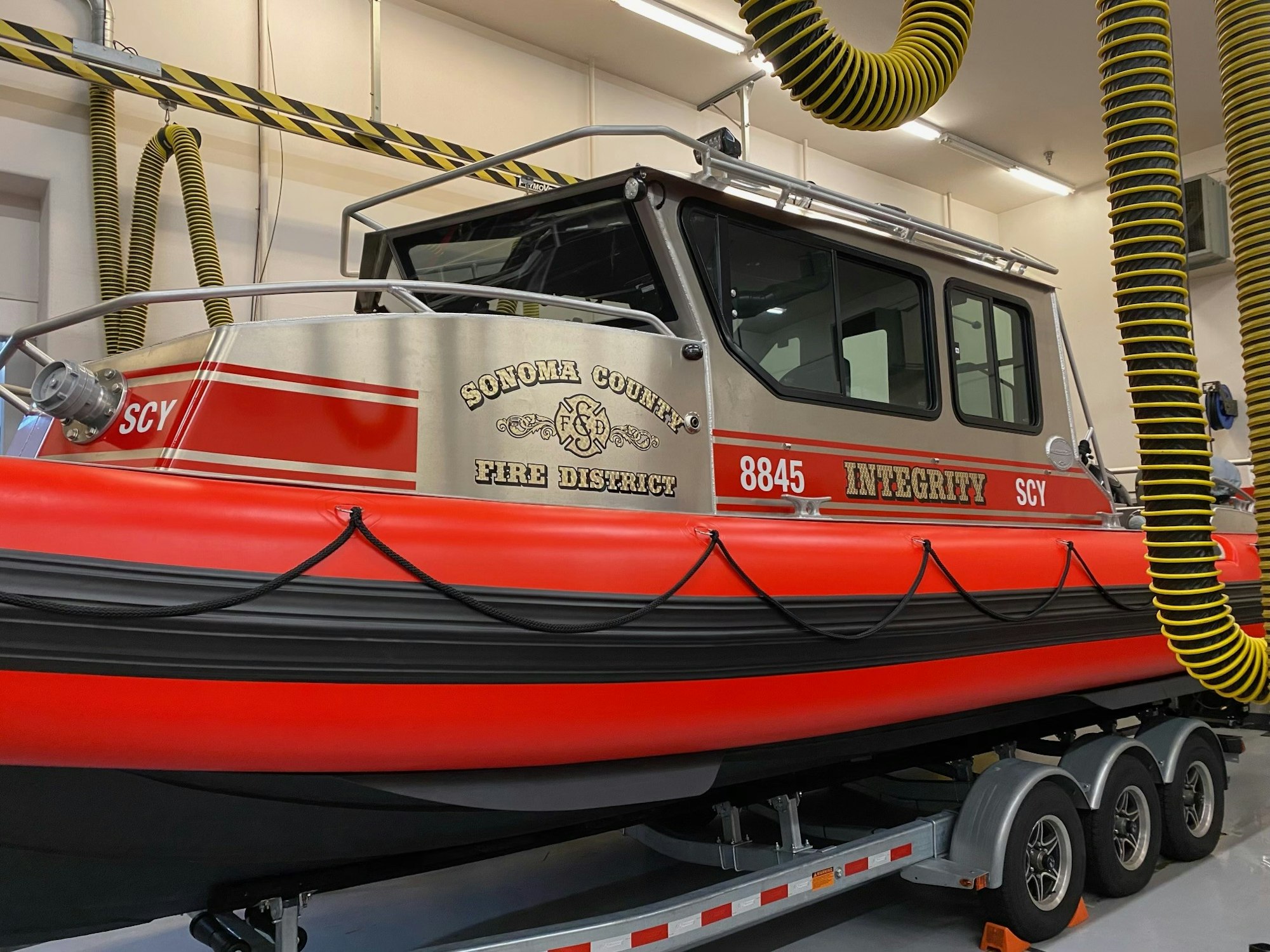 A fire rescue boat labeled "Sonoma County Fire District - Integrity" on a trailer in a garage.