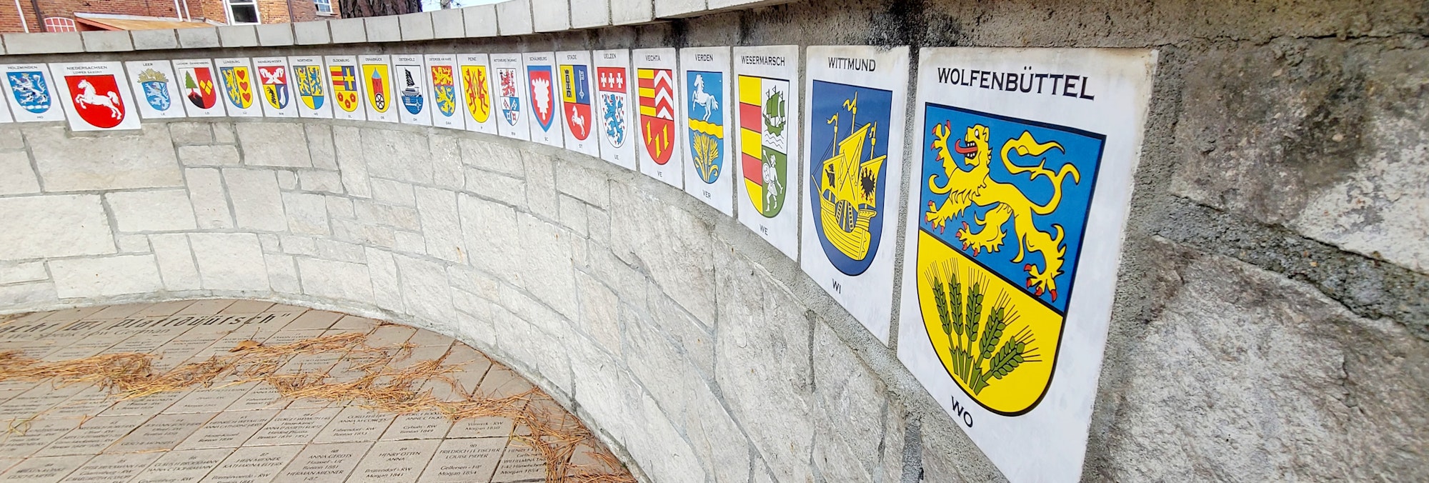 The image shows a series of coat of arms displayed on a curved wall, representing various regions or cities.