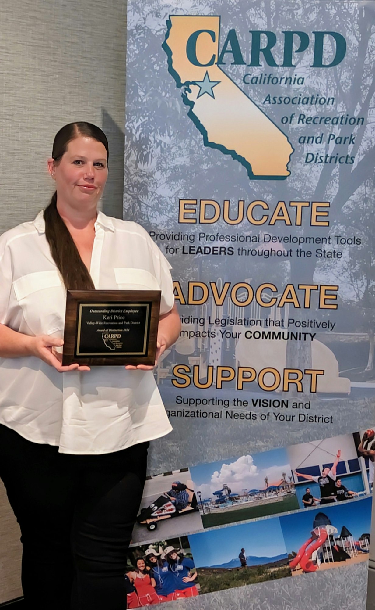 A person holding an award plaque in front of a banner for the California Association of Recreation and Park Districts (CARPD).