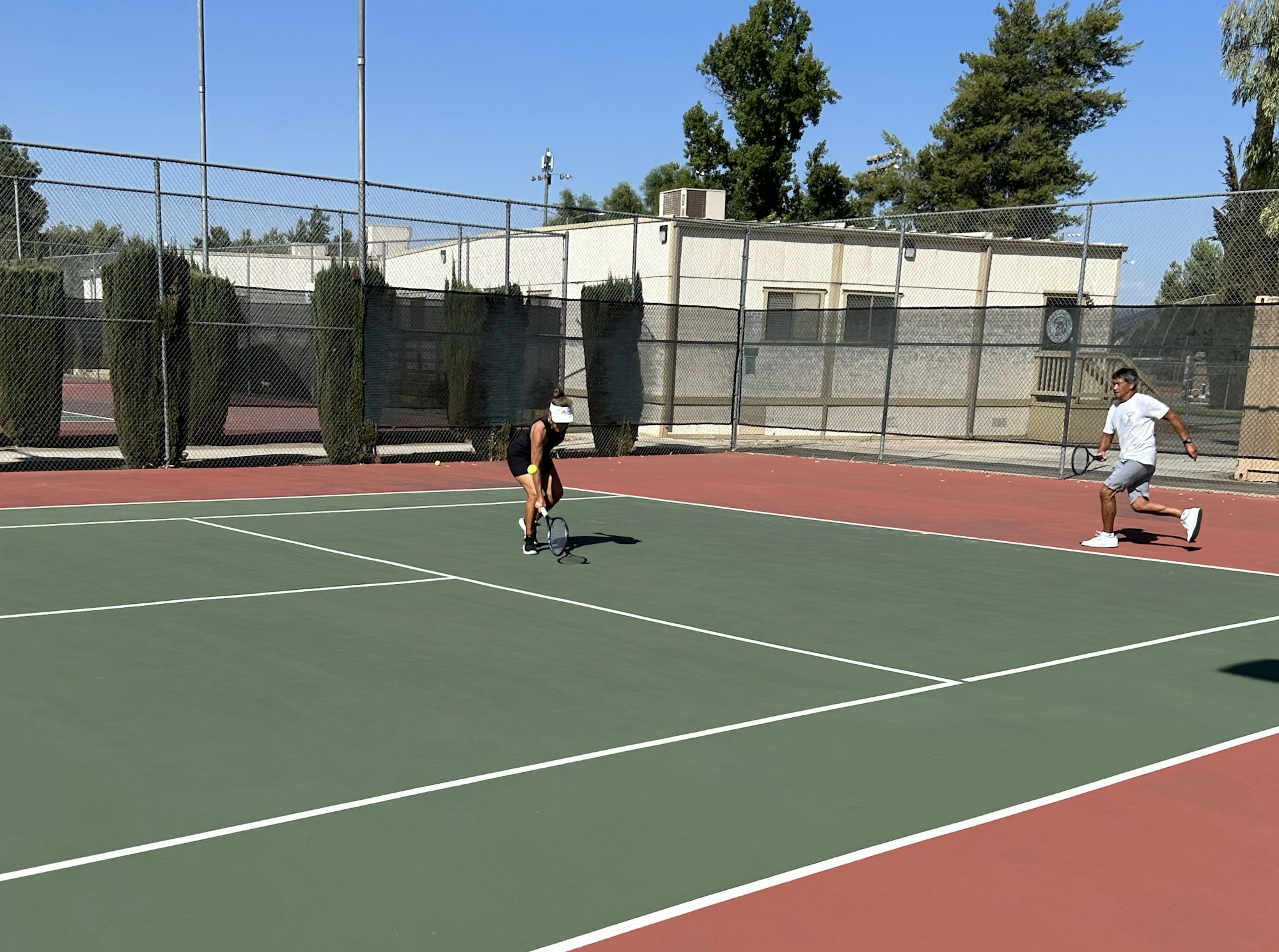 Two people playing tennis on an outdoor court.